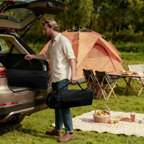Man carrying Portable Folding Camping Table With Carry Bag And Detachable Storage Pockets at a campsite