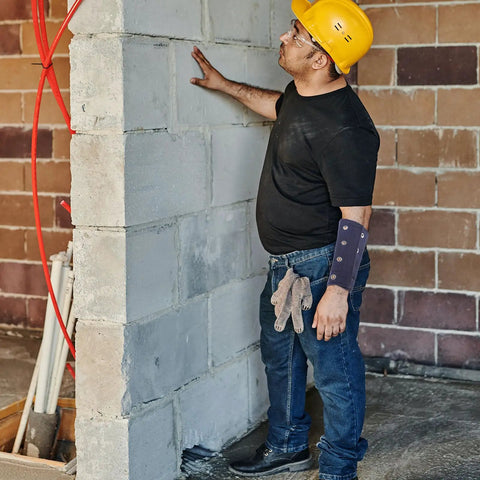 Man in black shirt wearing Kick Ass Cut Resistant Wrist Sleeves Breathable Lightweight Arm Guards for construction work.