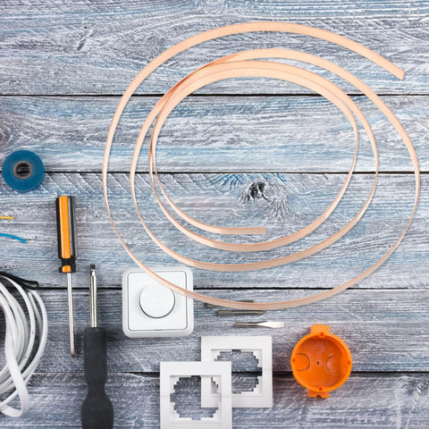 Pure Copper Sheet Roll 1mm Thick By 10mm Wide By 2m Long for electrical and DIY projects, surrounded by tools on wooden surface