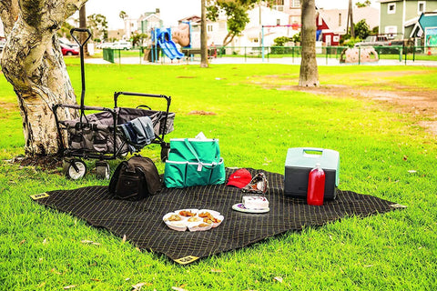 Heavy-Duty Padded Moving Blanket 80 x 72 Inches 4 Pack in outdoor use as picnic mat, visible black non-woven fabric with items on it.