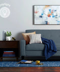Modern living room with gray sofa, abstract art, and daylight lighting, illustrating Led Plus Linkable Outdoor Flood Light with Motion Sensor.