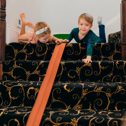 Children playing with Flexible 15 Foot Race Car Track For Kids With Suction Cups on stairway carpet