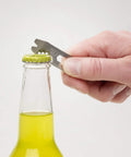 Hand using DoohicKey Keychain Multi Tool Stainless Steel 8 In 1 Bottle Opener to open a bottle