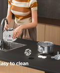 Woman cleaning Stainless Steel Cat Water Fountain Two Point Six Liter Ultra Quiet Pet Fountain parts on kitchen sink.