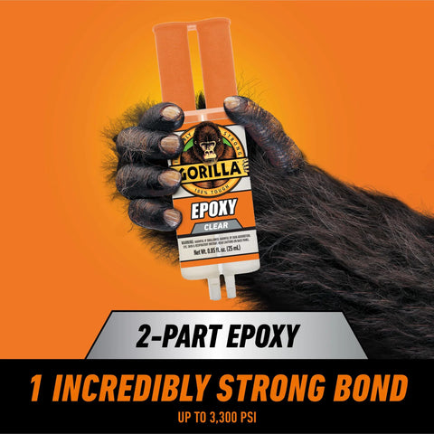 Front view of Gorilla 2-Part Epoxy syringe, clear, 0.85 oz, dual-cartridge held by a gorilla hand on orange background