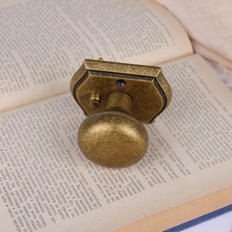 Privacy Door Knob For Interior Doors In Antique Brass resting on a book, showcasing its classic decorative hardware design.