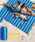 Family sitting on blue stripe 7x7 ft Extra Large Beach Blanket Waterproof And Sand Free For 3 To 4 People on sandy beach with stakes
