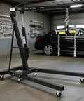 Bad Boy Heavy Duty Folding Hydraulic Engine Hoist And Cherry Picker in garage, designed for effortless lifting of 4400 pounds.