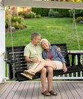 Couple sitting on Heavy Duty Outdoor Patio Porch Swing 880 Lbs Capacity 4ft Wooden Hanging Bench with Adjustable Chains, Black Finish