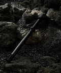 Thru Axle Adapter For Boost Forks, 1.0mm Thread Pitch laying on rocks, designed for 120mm to 185mm MTB hubs, includes handle.