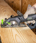 Person using Genesis Mini Circular Saw 4.0 Amp 4-1/2 Inch With 24-Tooth Carbide Blade for precise cut on wood.