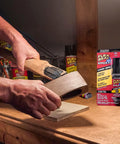 Applying Boss Level Liquid Epoxy Adhesive for ultimate waterproof fixes on a wooden hammer handle in a workshop.