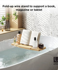 Aquala Extendable Bathtub Tray Caddy With Book Stand And Wine Glass Holder in use over a filled bathtub with book and wine.