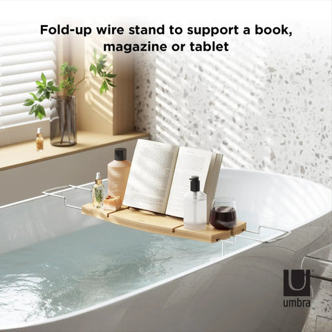 Aquala Extendable Bathtub Tray Caddy With Book Stand And Wine Glass Holder in use over a filled bathtub with book and wine.
