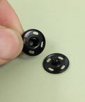 Close-up of black fabric snap buttons from 180 Piece Hook And Eye Sewing Kit All In One With Buttons And Closures For Skirts Pants And Dresses Fabric Snap Buttons Garment Snaps DIY Craft Essentials In Handy Storage Box.