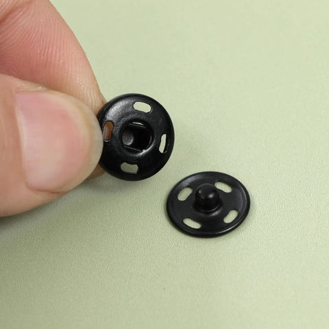Close-up of black fabric snap buttons from 180 Piece Hook And Eye Sewing Kit All In One With Buttons And Closures For Skirts Pants And Dresses Fabric Snap Buttons Garment Snaps DIY Craft Essentials In Handy Storage Box.