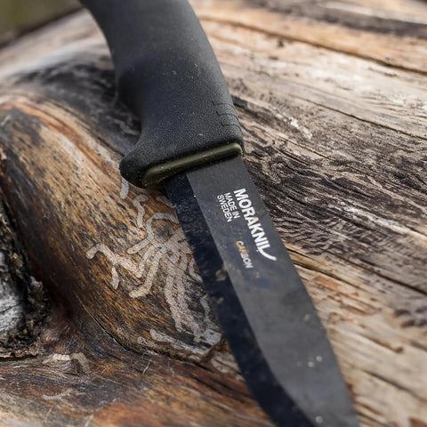 Bushcraft Survival Fixed Blade Knife with carbon steel black DLC coated blade on wood background