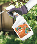 Gloved hand spraying Captain Jacks Copper Fungicide Ready To Use Spray For Organic Gardening 32 Oz on garden plants.