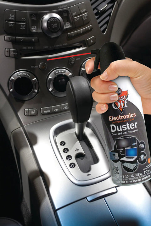 Hand using Dust Off Disposable Duster 7 Oz With Precision Straw for quick dust removal on car console and electronics.