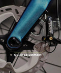 Juin F1 hybrid hydraulic disc brake caliper installed on blue bicycle frame near rotor (side view).