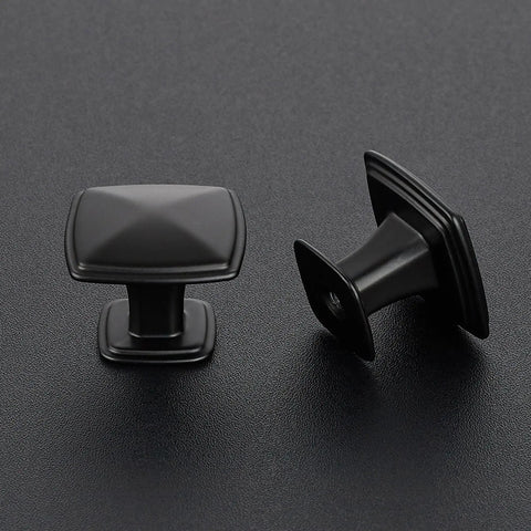 Two matte black square knobs on dark surface, part of 10 Pack Black Square Cabinet Knobs For Cabinets And Drawers One Hole Dope Rugged Heavy Duty Metal Hardware Easy Install Modern Kitchen Upgrade Durable Matte Black Knobs.