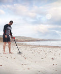 Minelab Vanquish 440 metal detector on a sandy beach; black shaft with red control housing