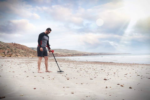 Minelab Vanquish 440 metal detector on a sandy beach; black shaft with red control housing