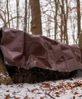 Heavy Duty Poly Tarp Cover 16 Mil, brown, covering firewood in a snowy forest, with grommets and reinforced edges, 6 x 8 Feet