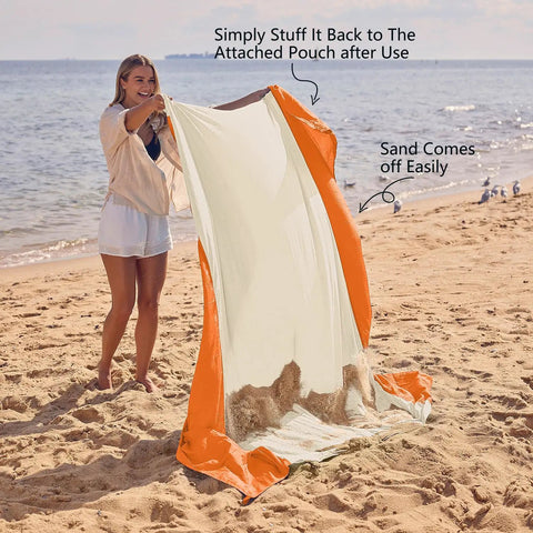Person holding Sandproof And Waterproof Beach Blanket 7x7 Ft Extra Large Mat With Stakes showing sand easily shakes off.