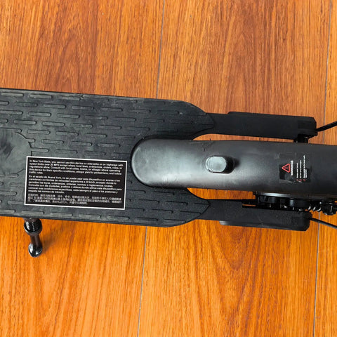 Powerful Electric Scooter For Adults With 500W Peak Motor, 18 MPH Top Speed; close-up of deck with grip tape and warning label.