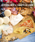 Top view of 11x5 in wooden mini charcuterie board with handle amid cheese, crackers, grapes.