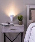 Plug In Wall Sconce Uplighter With GU10 Spotlight Wash Light, Touch Button Base, illuminates a bedside area next to a plant.