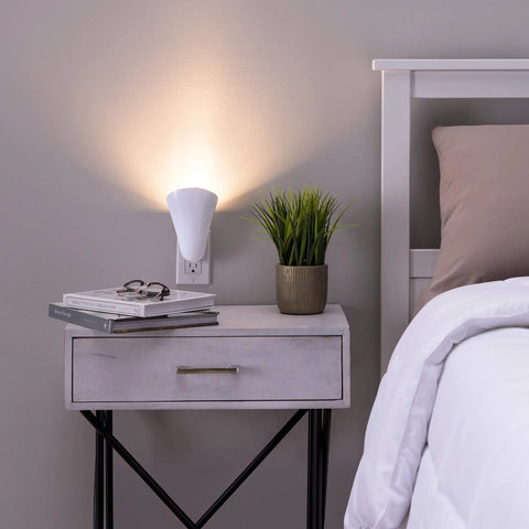 Plug In Wall Sconce Uplighter With GU10 Spotlight Wash Light, Touch Button Base, illuminates a bedside area next to a plant.