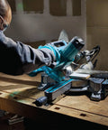 Person using Eight And A Half Inch Sliding Compound Miter Saw With Ten Point Five Amp Direct Drive Motor Packs Five Thousand RPM Bevels Zero To Forty Seven Degrees Portable Thirty Point Six Pounds Cuts Up To Twelve Inches At Ninety Degrees on a workbench.