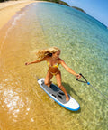 Person using Go-To Wind Wingfoil And Hydrofoil Board Kit With Inflatable Wing Pack for Portable Foiling on clear water beach.