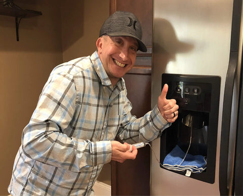 Man using a Universal Fridge Water Line Thaw Kit That Quickly Unfreezes Your Refrigerator Dispenser Easy Install Includes 36 Inch Flex Tube And 36 Inch Smooth Glide Tube Works On Nearly All Refrigerator Brands on a fridge water dispenser.