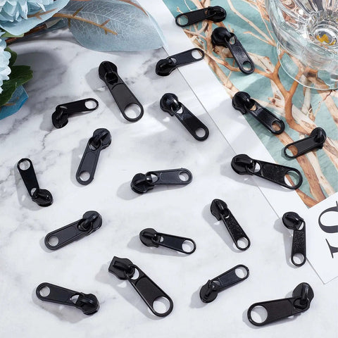 Zipper Puller Replacement Kit 32 Pieces In Four Sizes displayed on a table, black durable plastic beads, DIY tools for coats and luggage.