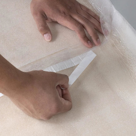 Hands removing protective layer from Top Shelf 100 Square Foot Laminate And Engineered Wood Flooring Underlayment Roll.
