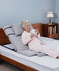 Sturdy Greenlemon Electric Bed Backrest Lifter With Remote Adjustable Support For Heavy Duty Use Up To 300 Pounds Load Capacity Flexible Angle Settings From Four To Sixty Eight Degrees Perfect For Relaxing Or Reading. Elderly woman sipping tea resting on support.