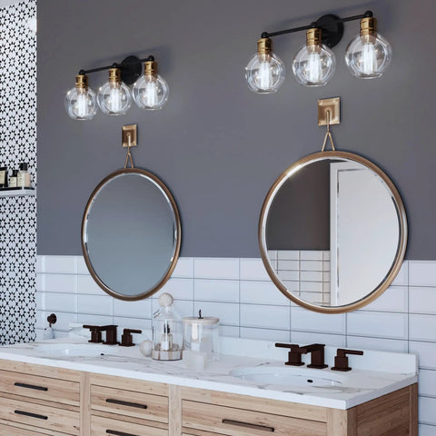 Coastal 3 Light Bath Vanity Light With Clear Glass Globes In Antique Bronze Finish above double mirrors in a bathroom setting