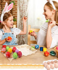 Mother and daughter painting Easter eggs with 12 count clear plastic egg cartons bulk pack on table.