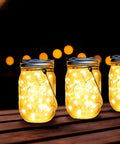 Solar Mason Jar Lid Lights 12 Pack With 30 LEDs For Outdoor Use Fairy In A Jar Style String Lights glowing on wooden table