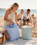 Family enjoying beach with Two Pack Large Wet Dry Bags For Swimwear And Laundry, Waterproof travel organizer in checkered design.