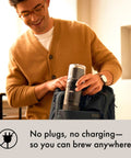 Person placing Rapid Brew Portable Coffee Maker For On The Go into backpack, highlighting plug-free, travel design