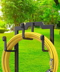 Black Garden Hose Reel Holder With Four Foot Design Modern Metal Water Hose Hanger Organizer Stand For Yard And Patio Keeps Hoses Tidy Easy To Mount Durable And Sleek Storage Solution displaying yellow hose on hooks.
