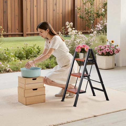 Three Step Folding Ladder With Wide Anti Slip Pedals And Comfort Handgrip Lightweight Aluminum 330 Lbs Capacity Portable Plant Support beside woman watering plants