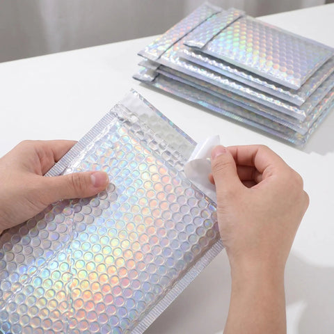 Hands sealing a Glitter Bubble Mailers 30 Pack Tear Resistant Shipping Bags For Jewelry Makeup Gifts And Small Items Thick Protective Mailers.