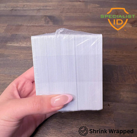 Top Shelf Blank Composite ID Cards For Retransfer Printers 30 Mil Pvc Pet Blend Cr80 Heavy Duty White Badge Stock held in hand.