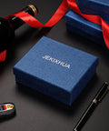 Blue gift box with JEKIXHUA branding, luxury pen, wine bottle with red ribbon, and car key on black surface