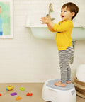 Toddler on The Real Deal Toddler Potty Training Chair 3-In-1 Potty Seat With Step Stool, gray step stool in bathroom.